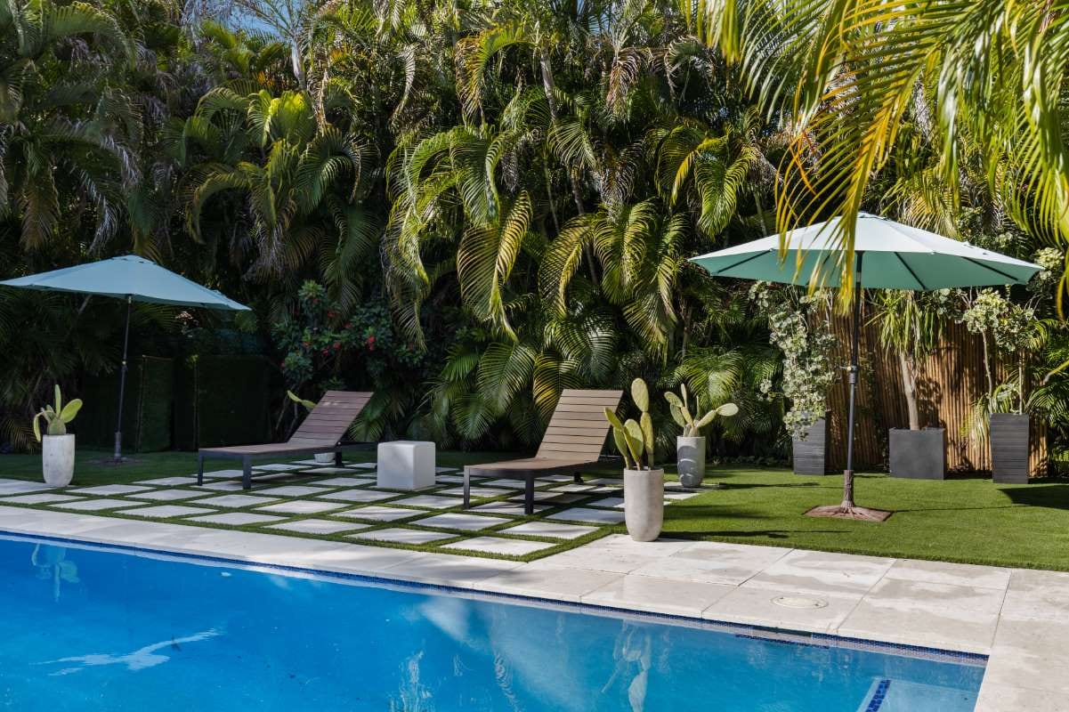 Backyard modern house with pool, artificial grass, stone path, trees, and chairs