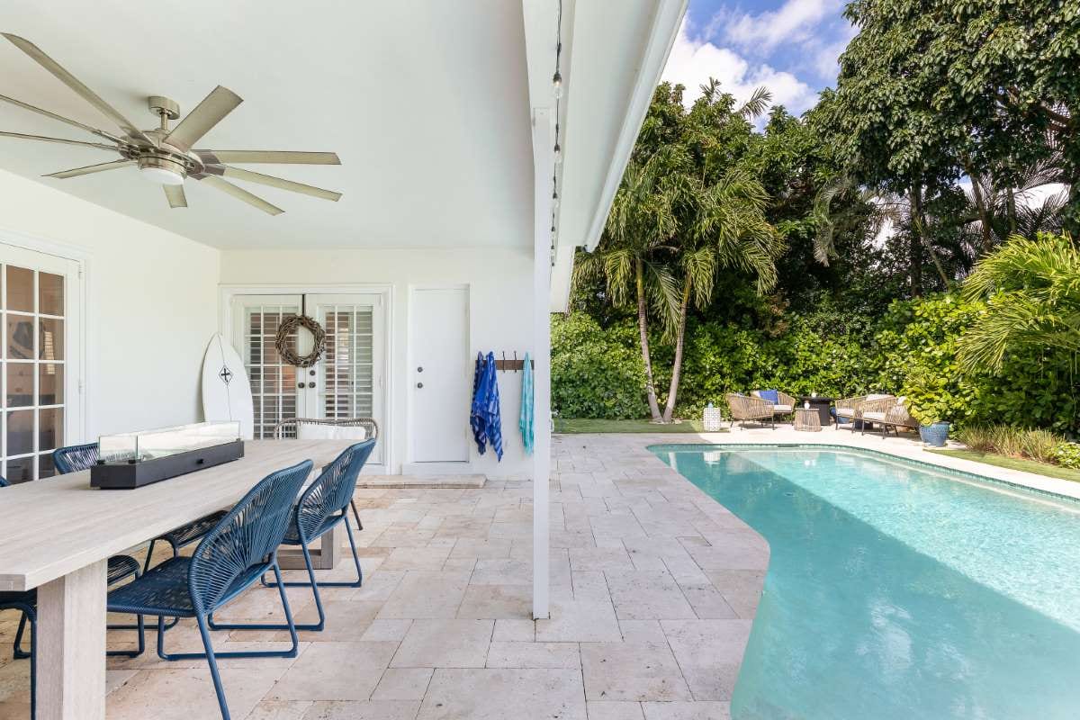 Modern backyard with swimming pool, artificial grass, stone path, trees, and patio chairs