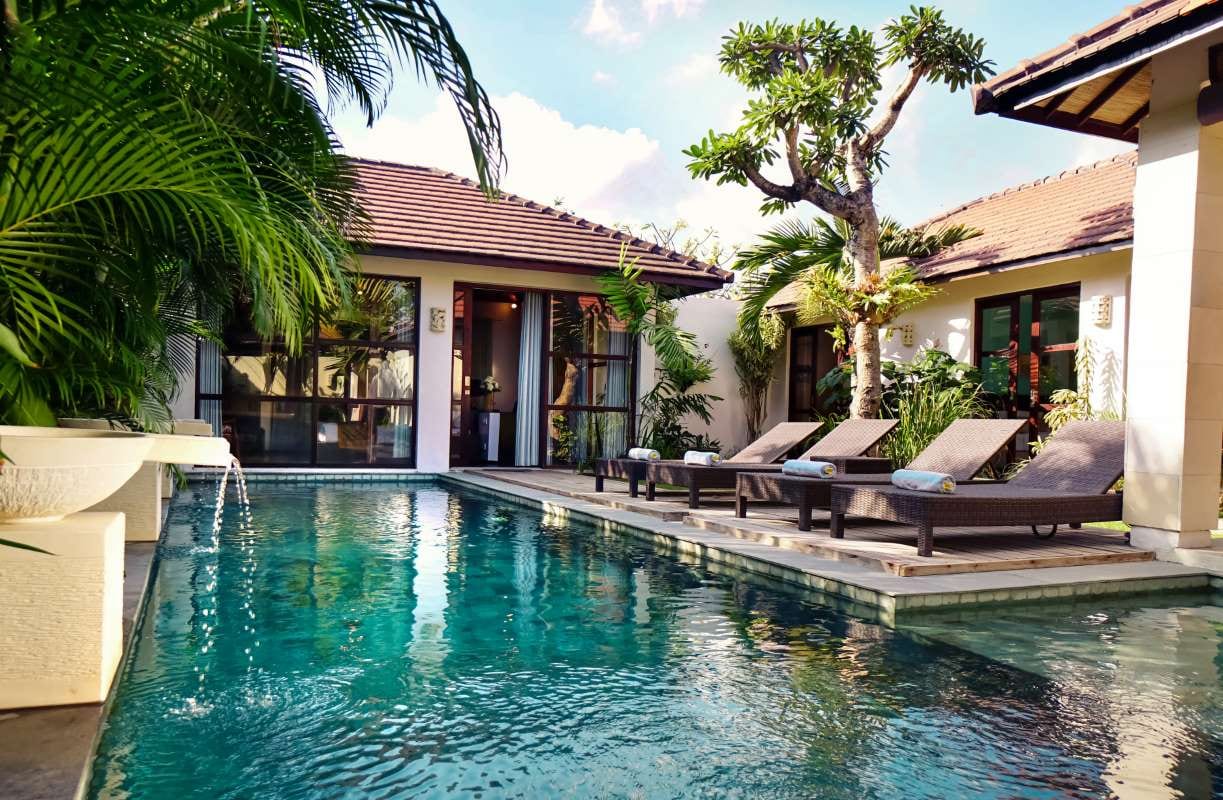 Contemporary home with tropical landscaping and a blue pool overlooking the garden