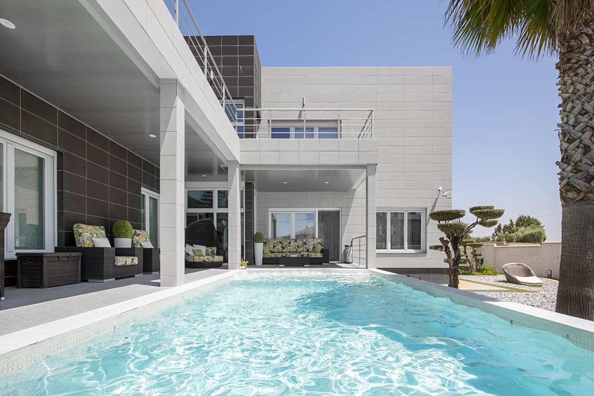 Minimalist detached house with pool, palm trees, and rattan porch seating
