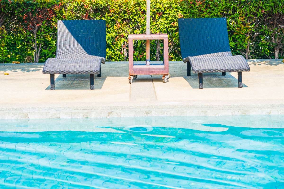 Empty chairs and tables beside a swimming pool