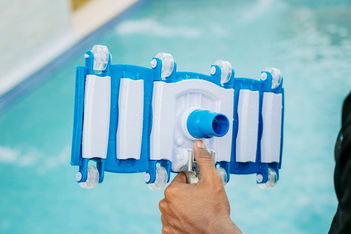 Hand holding a pool sweeper head for cleaning close up