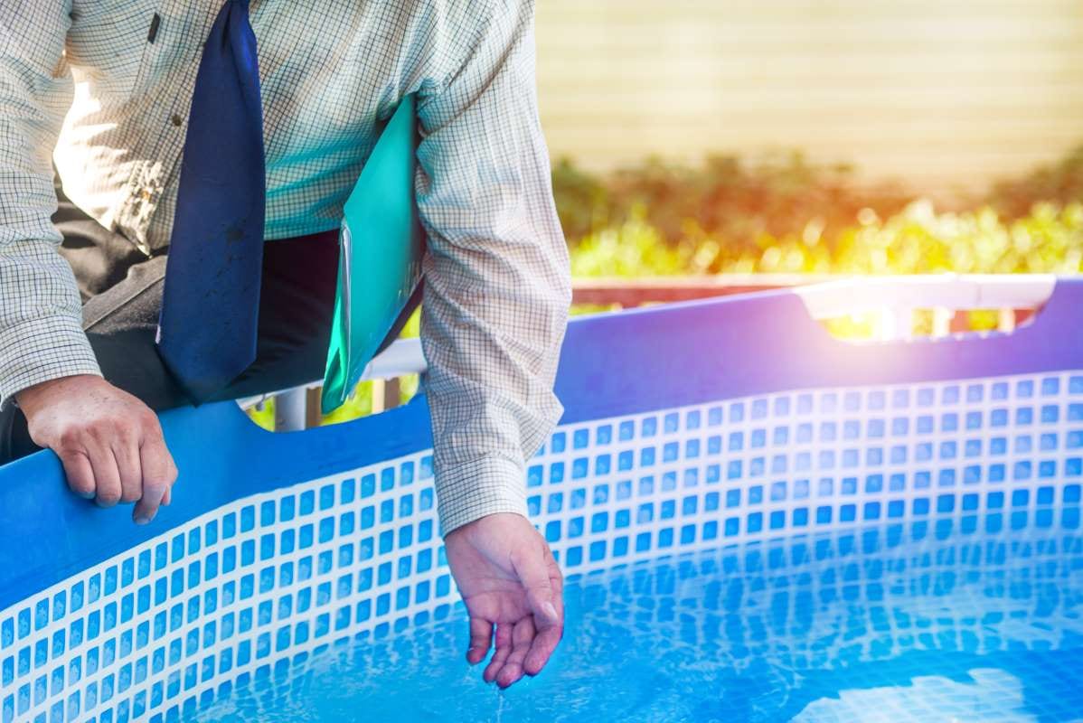 Person in business attire holding a folder while touching pool water