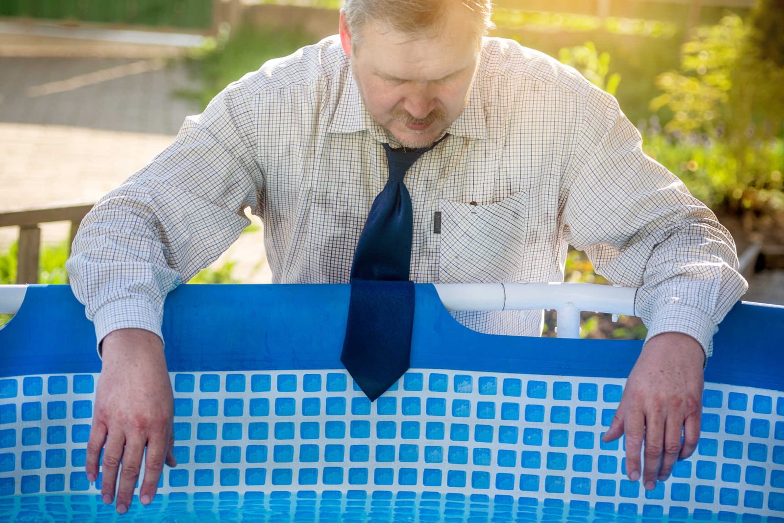 Businessman in suit suffering from heat beside a pool
