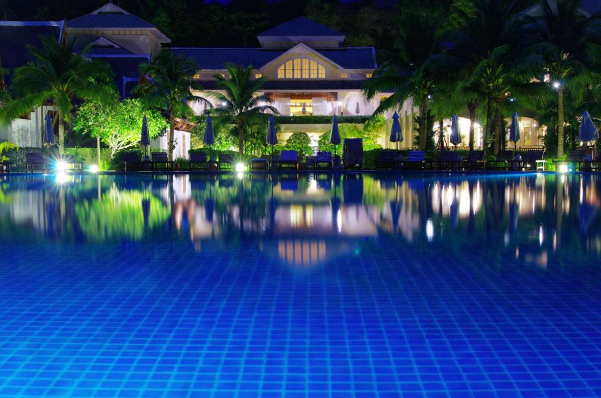 Hotel pool illuminated at night under calm reflections
