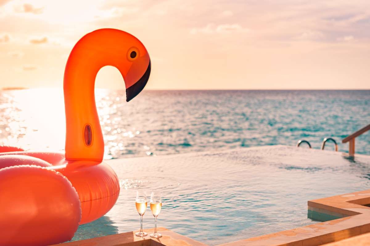 Luxury infinity pool at sunset with a couple and flamingo toy