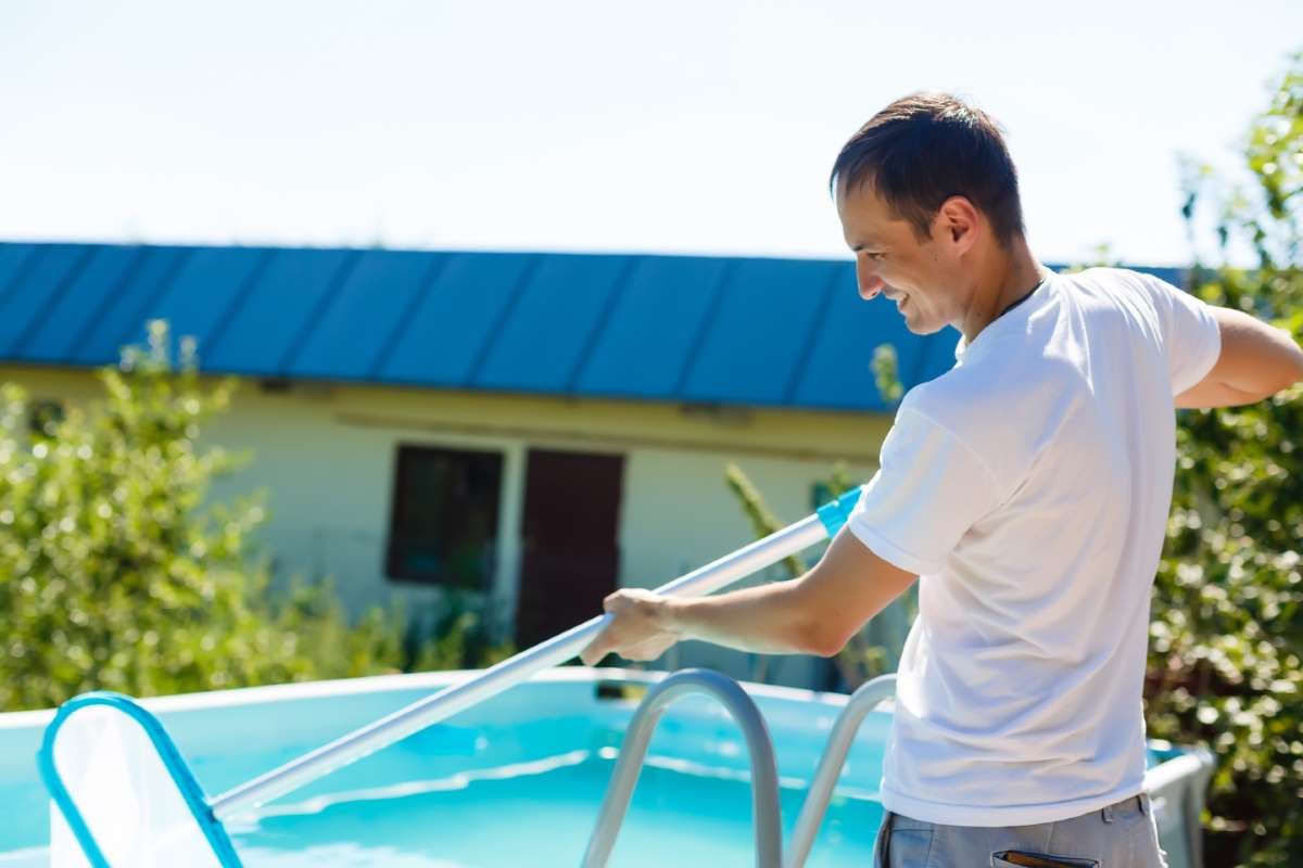 Man cleaning a pool at a country house in summer