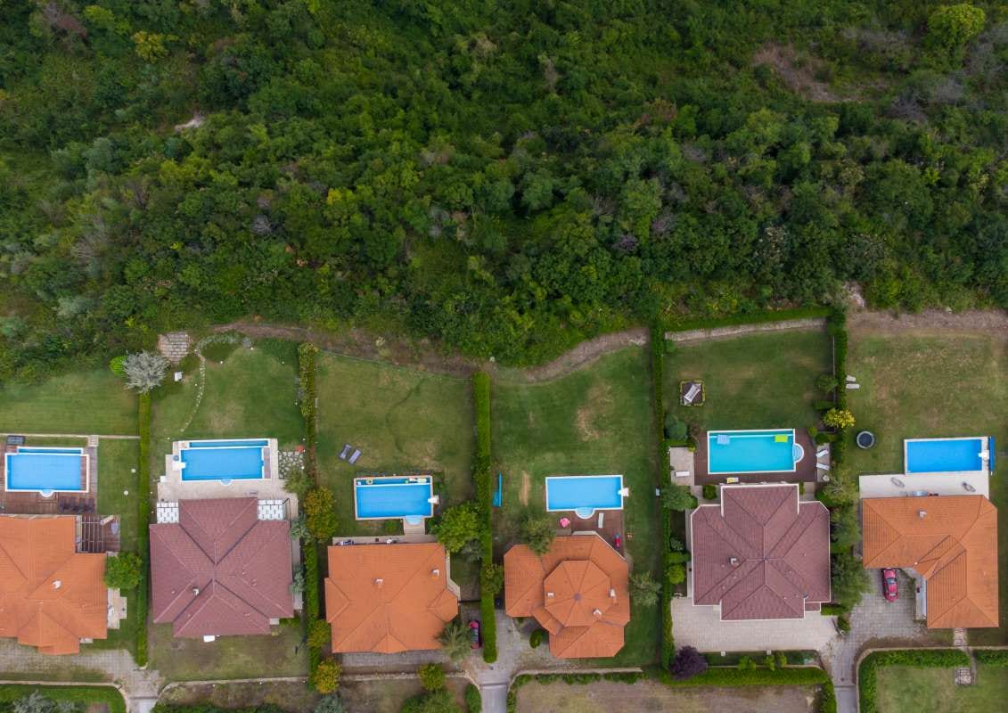 Aerial view of a modern cottage village with luxury homes, pools, and golf courses