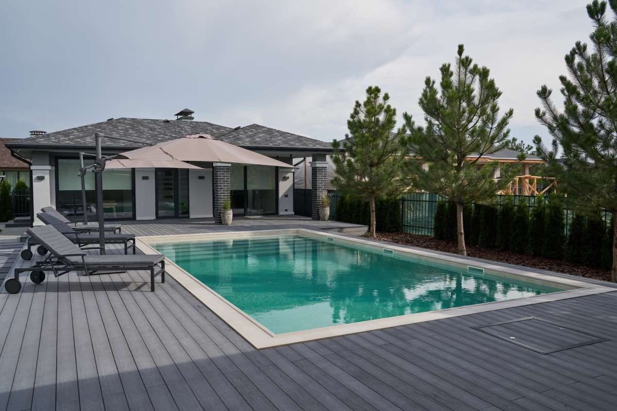 Modern villa with pool deck and outdoor swimming pool alongside apartment building