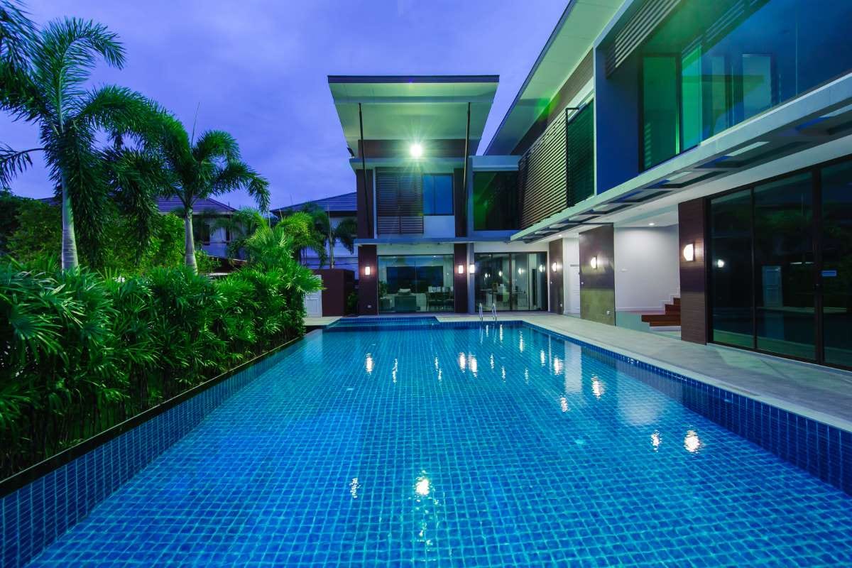 Blue swimming pool beside a blue pool house under clear daylight