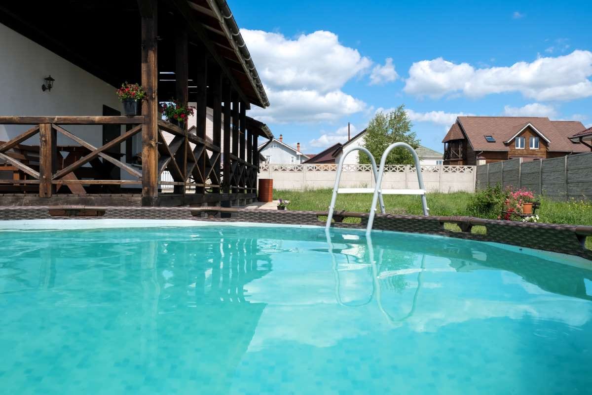 Private blue frame pool near a house on a sunny summer day
