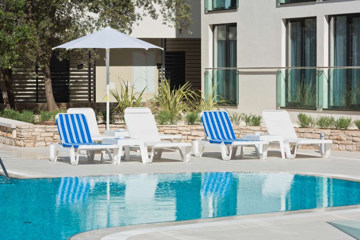 Sunbeds and umbrellas by a swimming pool on a sunny day