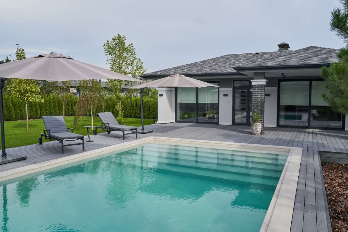Modern residential terrace with swimming pool, umbrellas, and chaise lounges