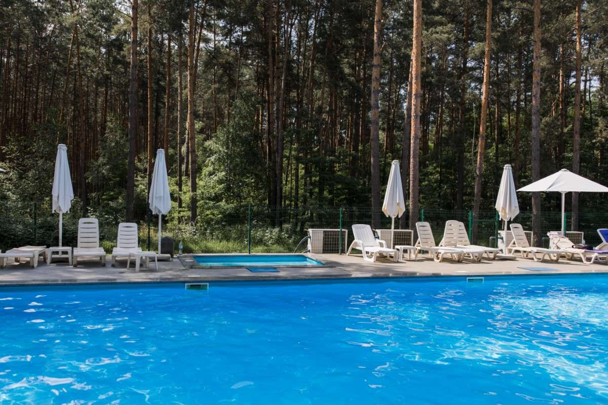 Swimming pool in a forest with umbrellas on a summer day