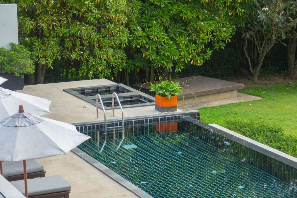 Swimming pool with metal stairs and green natural background