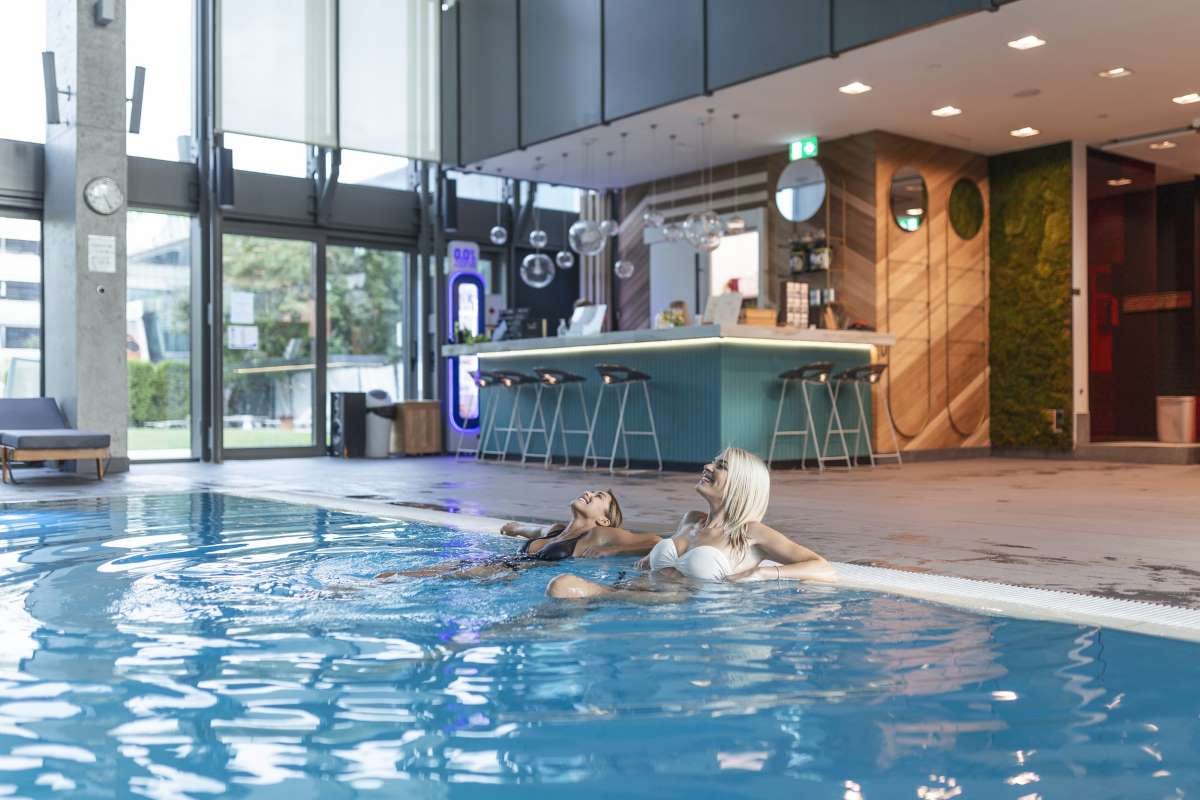 Two women friends smiling together by a swimming pool