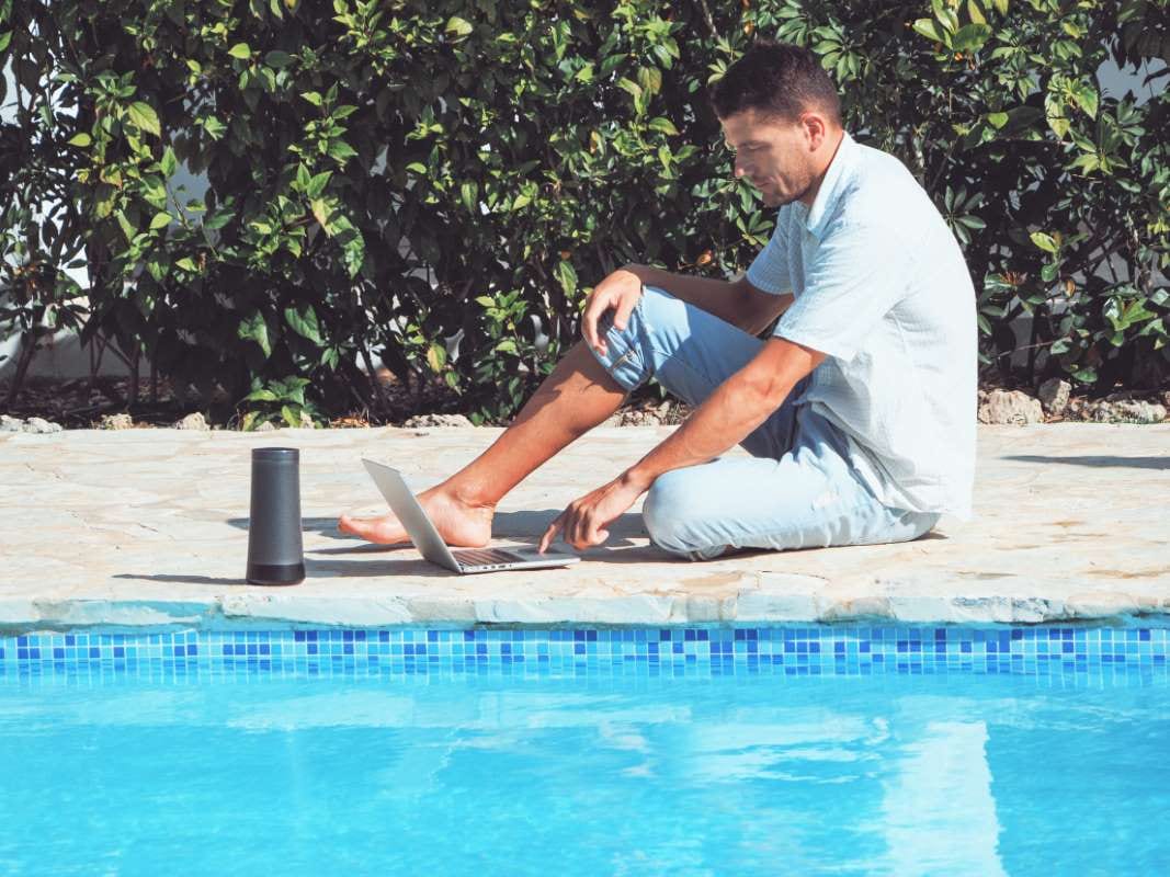 Young man working on a laptop near a swimming pool